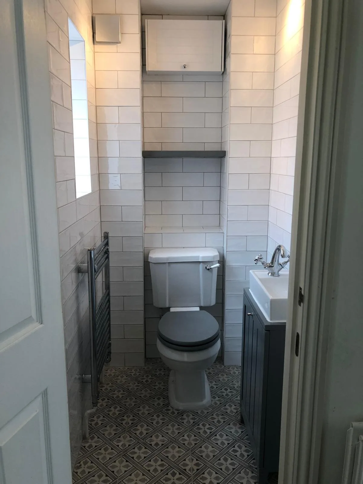 White metro-tiled cloakroom WC with a patterned floor