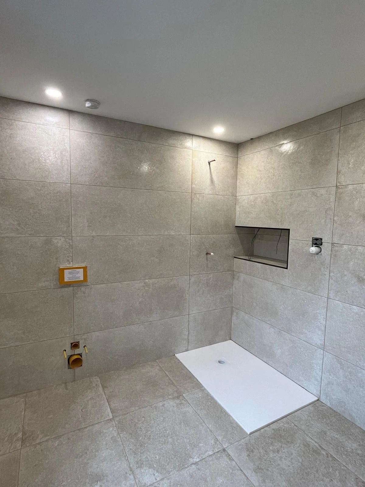 Grey stone-effect tiled walk-in wet room with a recessed shelf