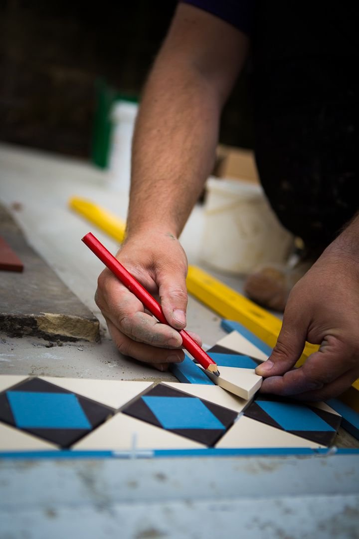 Setting out a blue, black and cream geometric tile pattern by hand