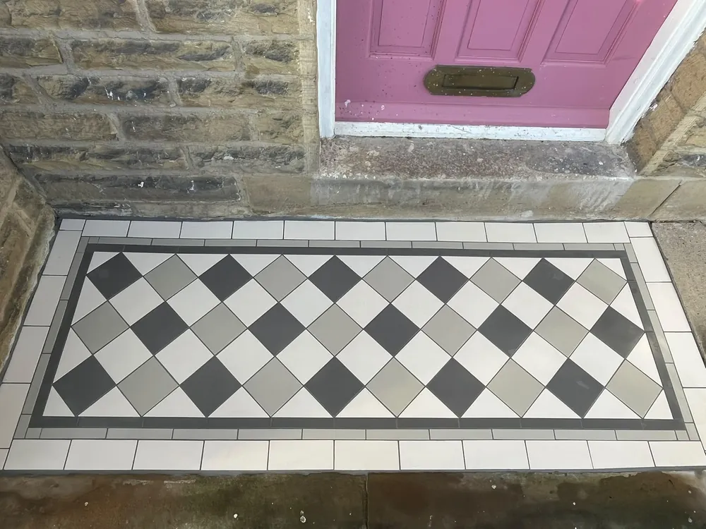 Victorian tiled front door step in grey, charcoal and cream diamonds with a border
